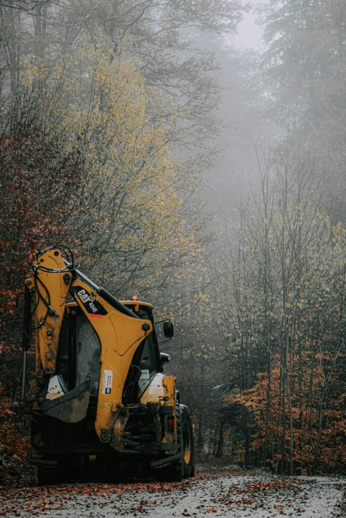 Digger on road near forest in autumn